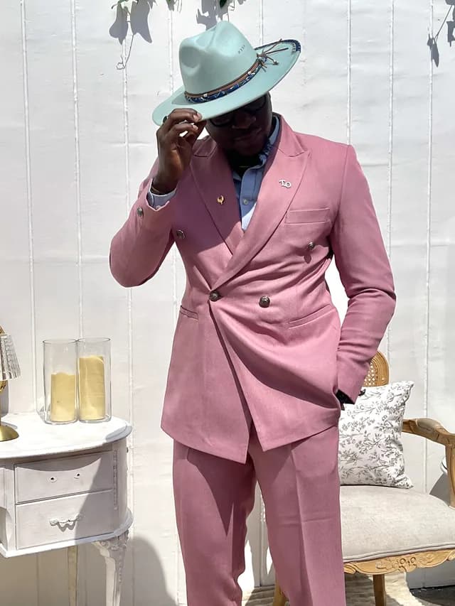 Theo in a rose double-breasted suit tipping a mint green fedora